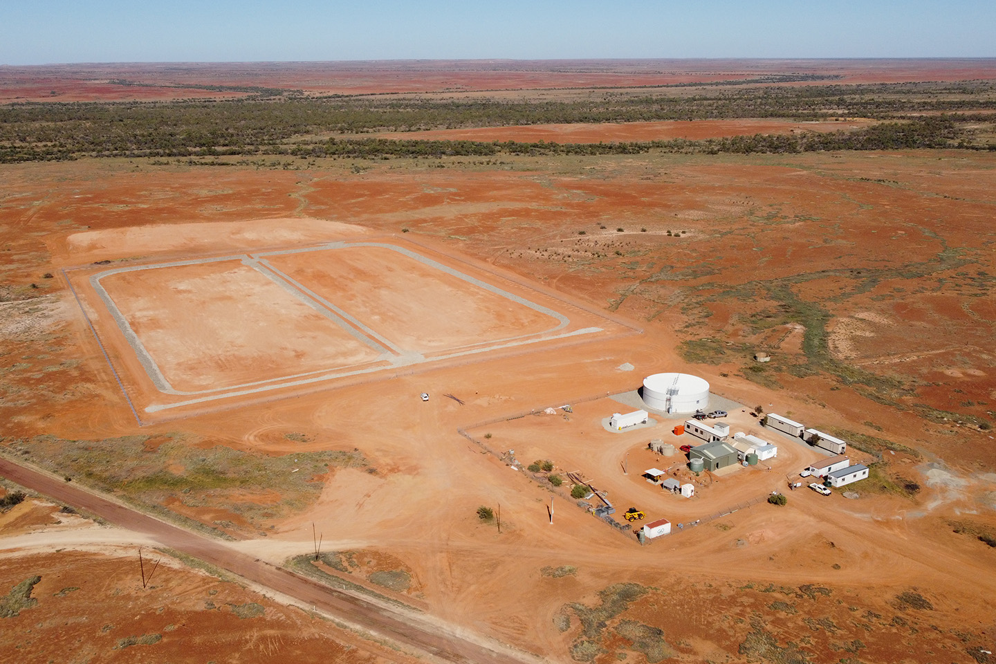 Aerial view of a small group of buildings in the middle of a large red dirt piece of land