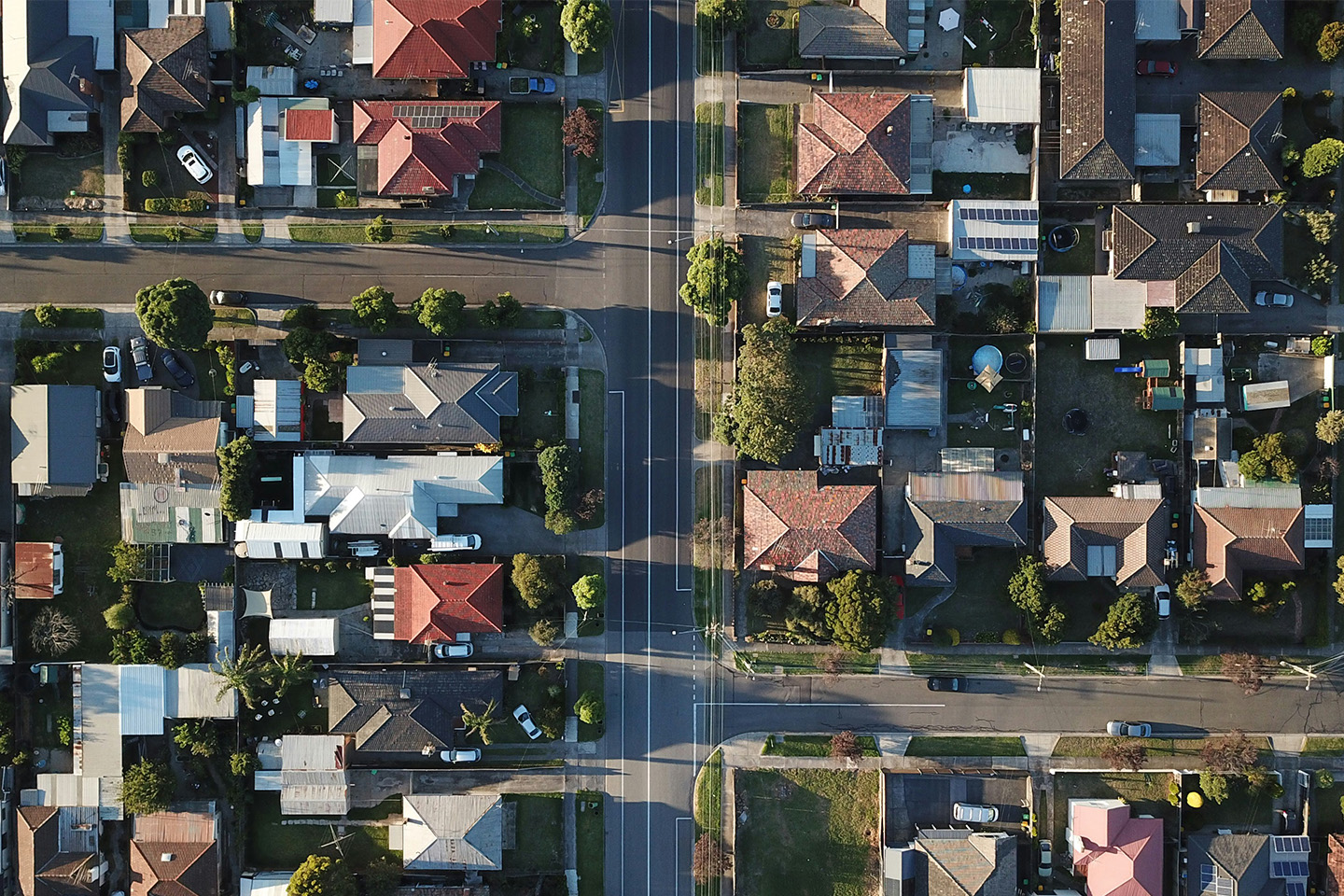 Aerial shot of suburbia featuring lots of houses and two roads intersecting in a cross in the middle