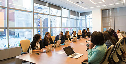 large group of women sitting around a long table in a corporate room