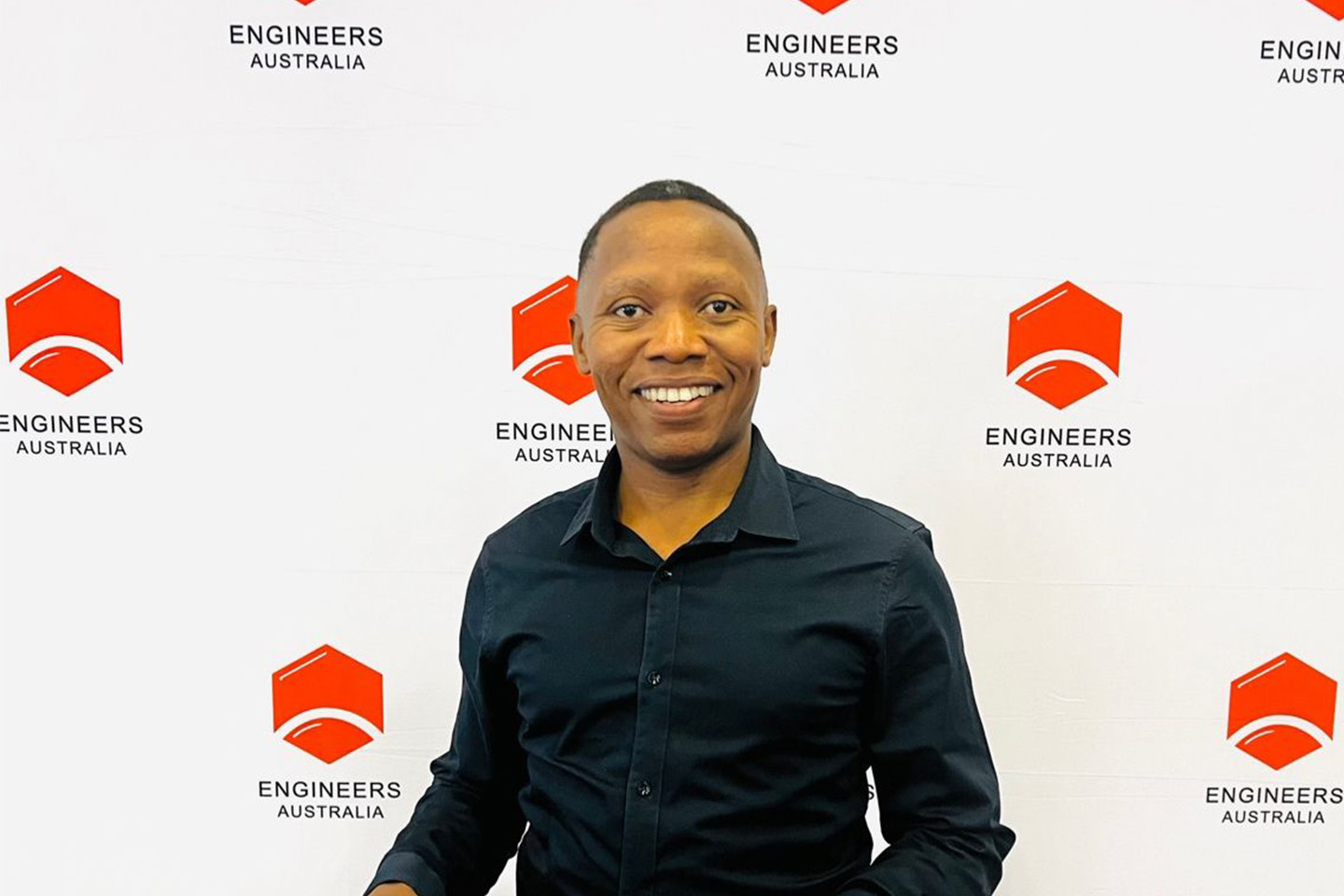 Douglas wearing a black dress shirt and smiling at the camera