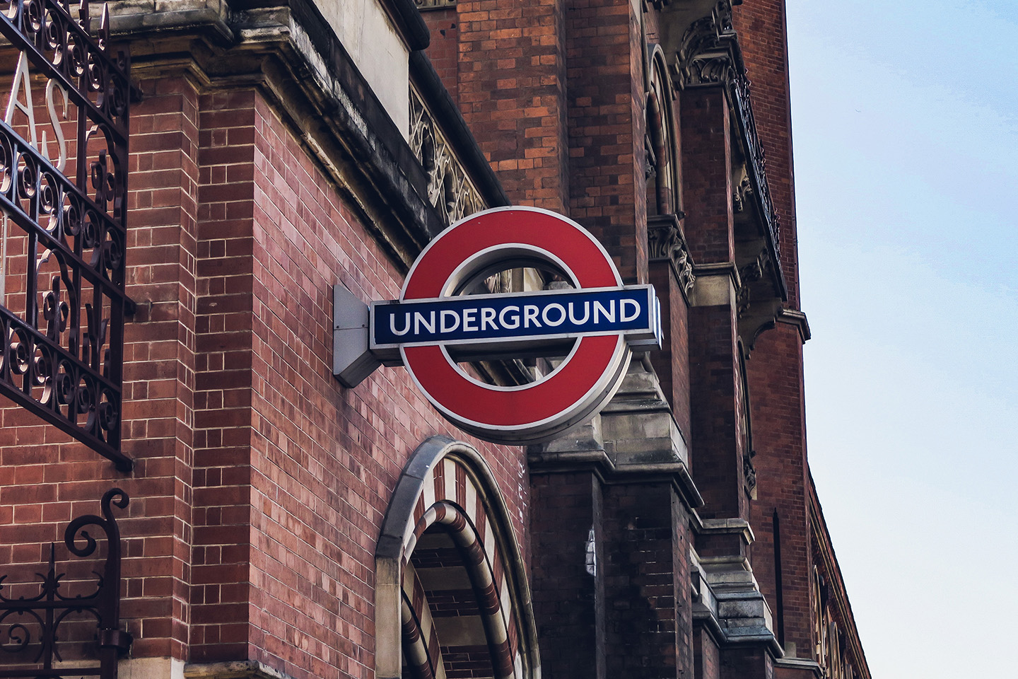 Blue and red sign for the London underground on the side of an old red brick building 