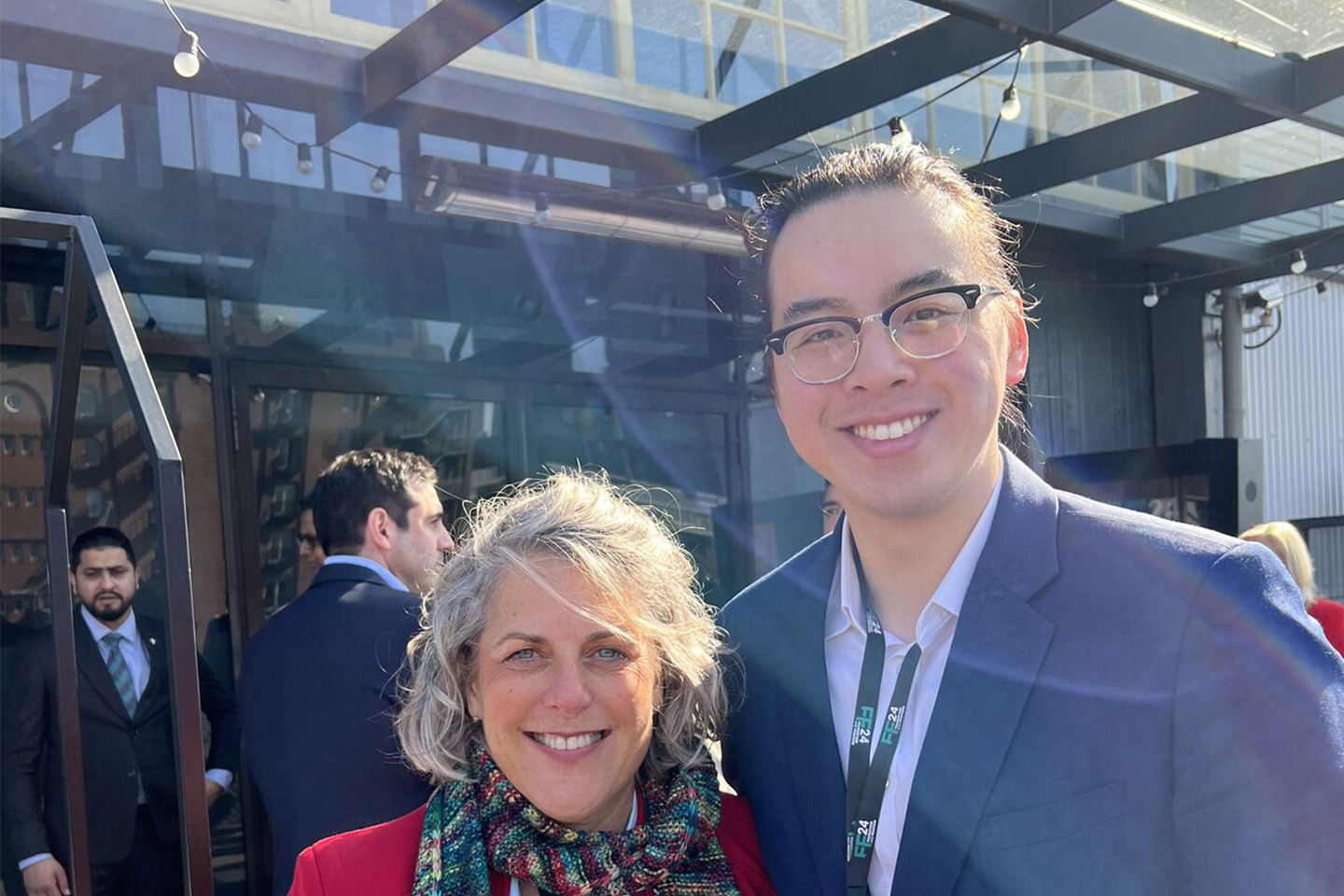 Romilly Madew and Adam Lee smiling for a photo outside a large building