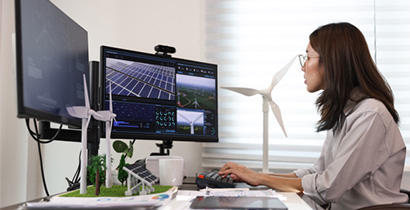 Woman looking at two computers with lots of code on the screen