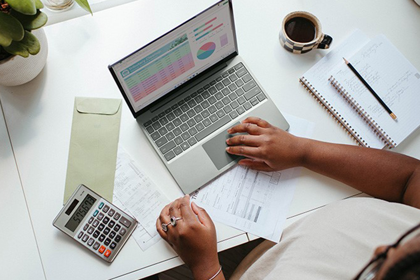 Woman typing on laptop with a calculator next to her