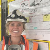 Eleanor Robson in a hard hat and orange high vis smiling at camera