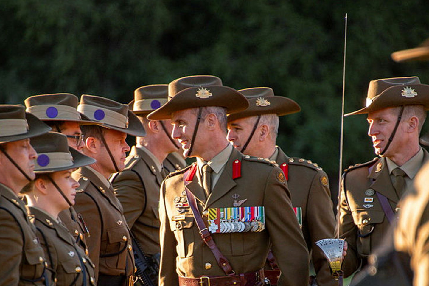 Uniformed officers standing in a line smiling at another officer