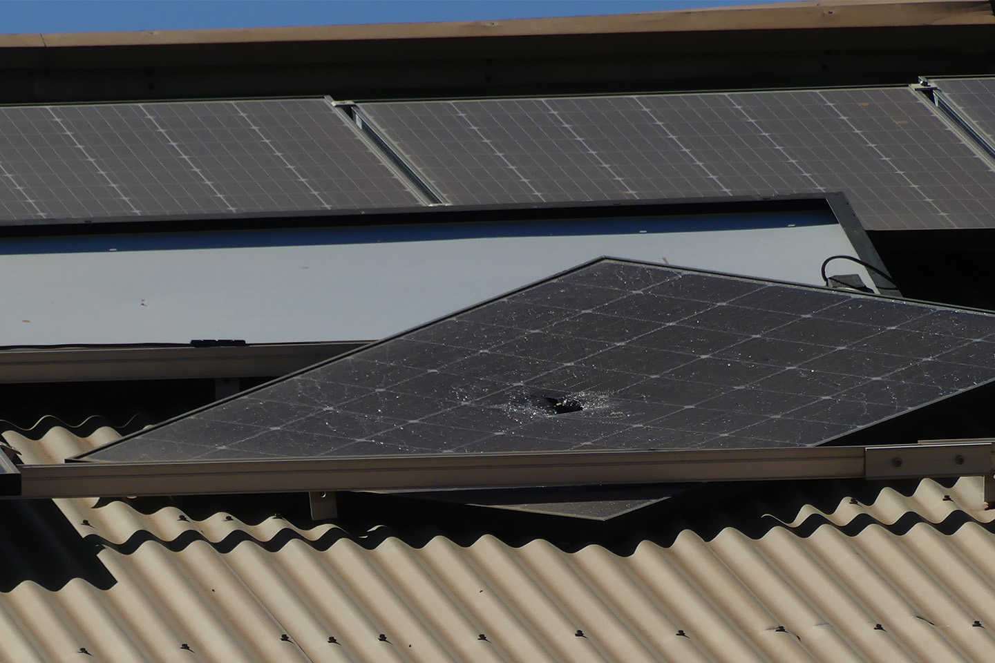 damaged solar panel with cracks through it, displaced on a tin rooftop