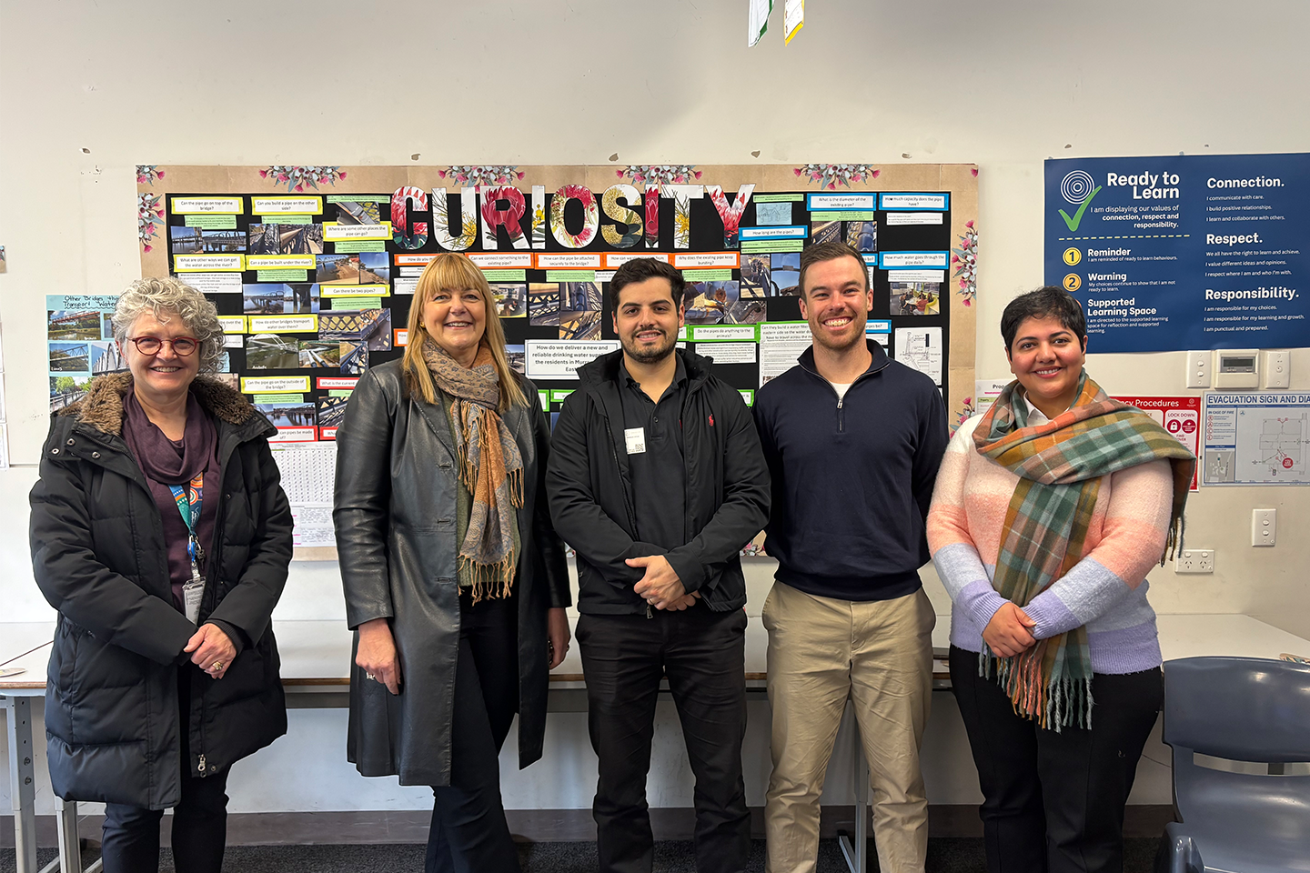 Image of Dr Sue Gaardboe, Jan Irvine, Lawrence Harms, Brayden Jenke and Nas Nabipour standing side by side, photographed in Oakbank School's classroom